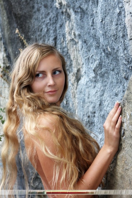 Totally naked girl Merit hits upon great poses in front of a sheer rock face 73469168