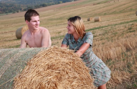 Young couple have sexual intercourse up against a round bale in a field 97279626
