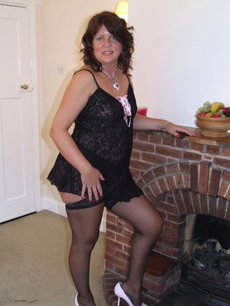 Thick mature woman Sandy looses her small tits from lingerie afore a fireplace 65840540