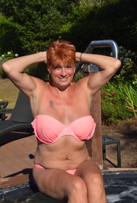 Mature redhead Dimonty shows her tits on a bench in a country field 78489885