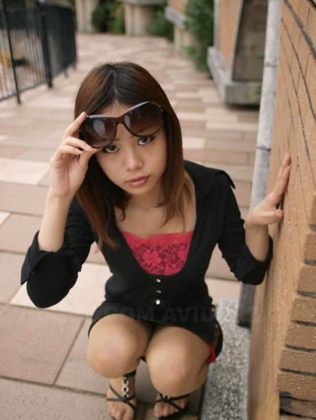 Fully clothed Japanese girl lifts up sunglasses to show her pretty face 76992484