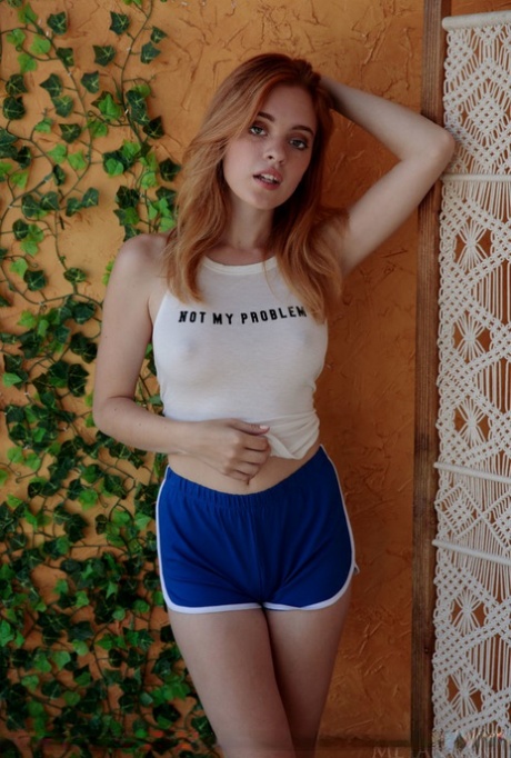 Young redhead Celeste Rasmussen disrobes to pose nude on a wicker chair 89777798