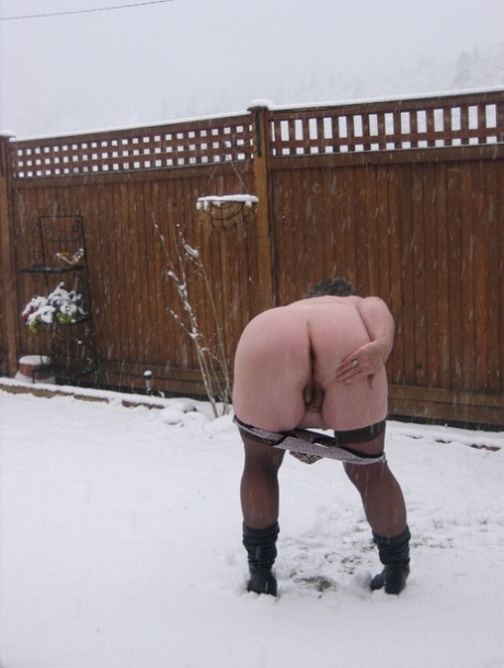 Naughty granny Girdle Goddess strips to her stockings and boots while it snows 16438869