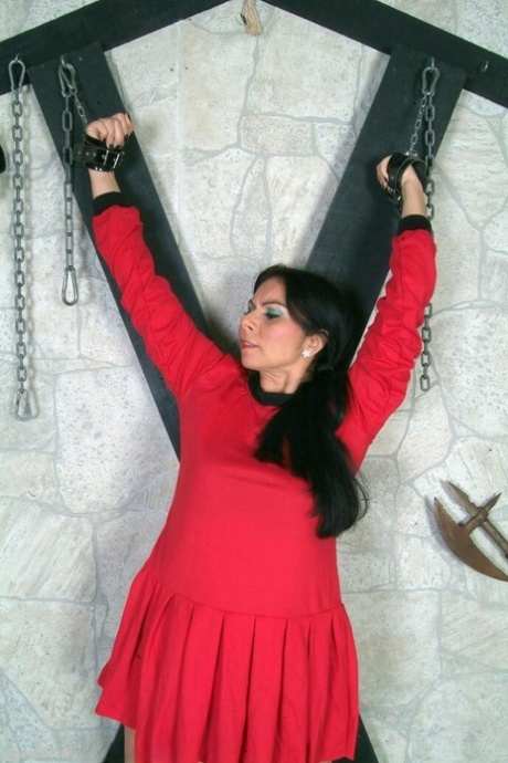 Dark-haired girl is attached to a St Andrew's Cross while fully clothed 85231969
