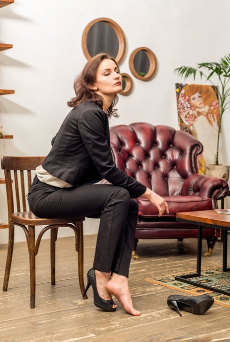 Fully clothed lady Leah takes off her high-heeled shoes and points at her feet 99134185