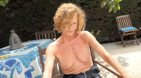 Redheaded granny Anne Swinger plays with her pussy while topless on a patio 12772783