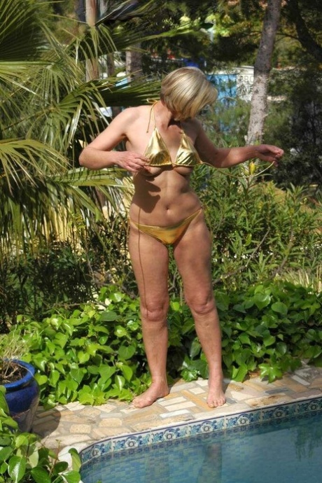 Older blonde woman Uschi Haller gets totally naked next to a swimming pool